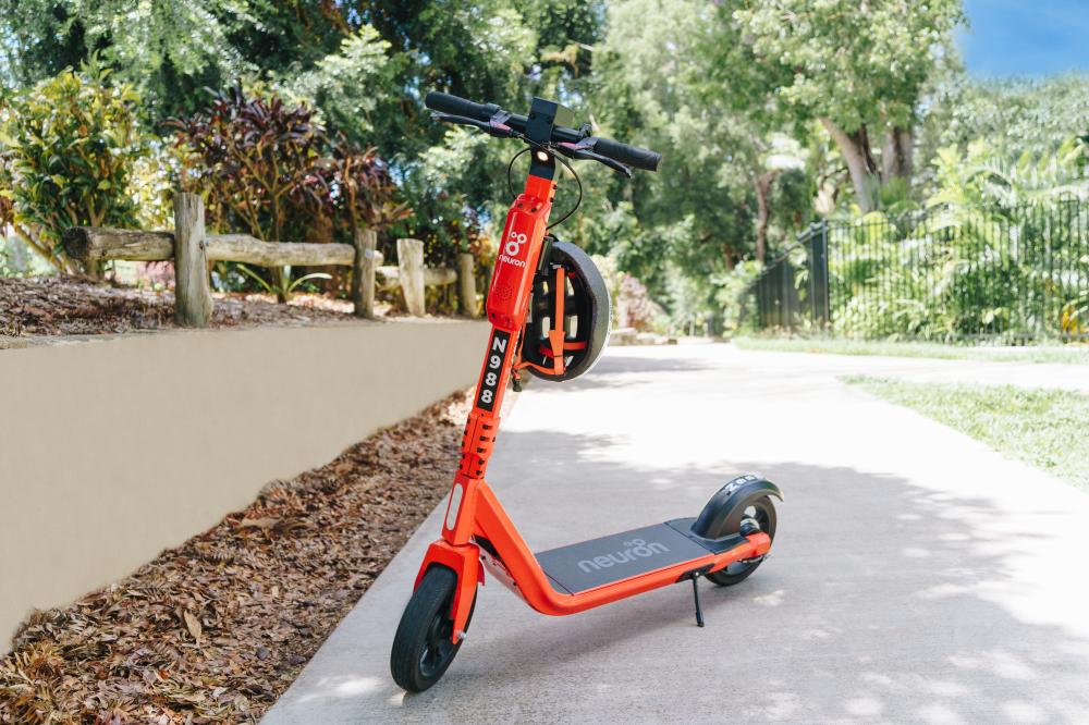 An orange e-scooter on a path in a park 