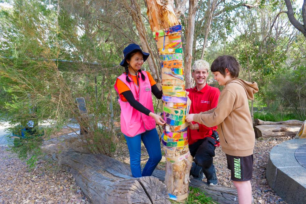 Two Kings Park education volunteers working on a tree activity with a boy.