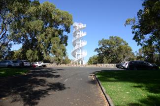 White, double spiral tower with stairs atop a hill.