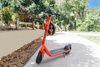 An orange e-scooter on a path in a park 