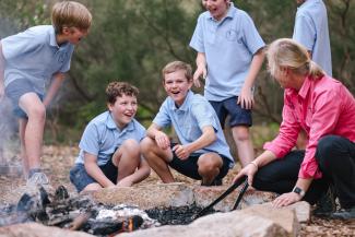 School children around a fire in the bush.