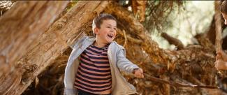 Child sword fighting with a stick in a natural setting.