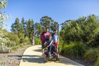 A girl in a wheelchair enjoys a playground with her family