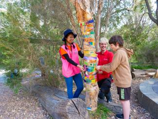 Two Kings Park education volunteers working on a tree activity with a boy.